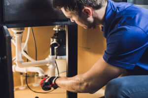 a plumber fixing a sink in a kitchen.