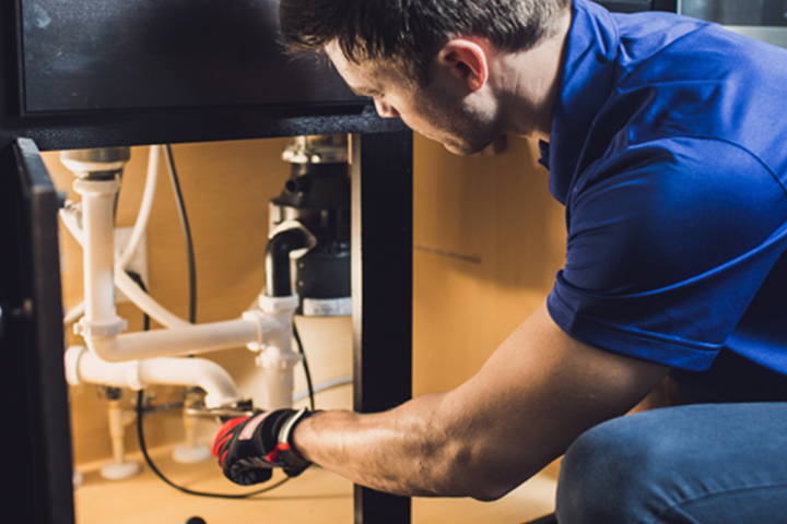 a plumber fixing a sink in a kitchen.