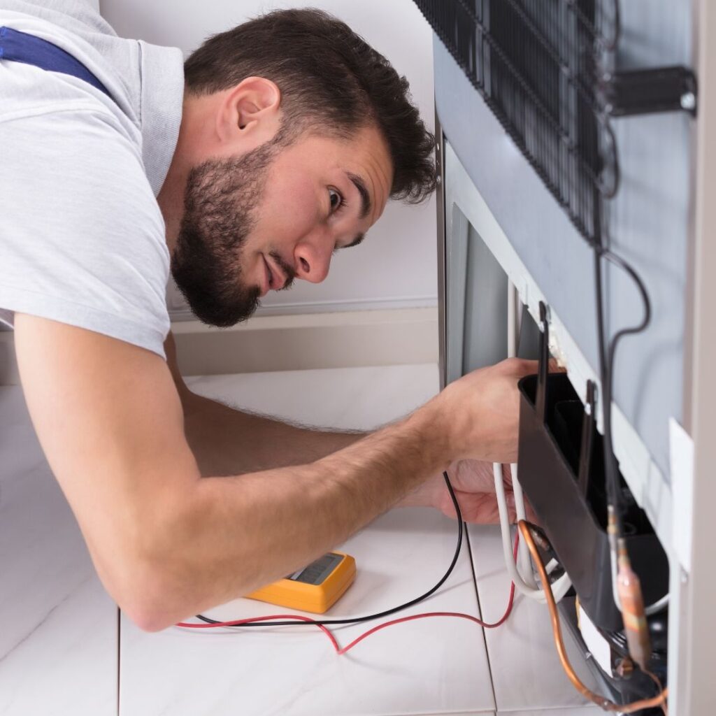 a man is working on an appliance in a kitchen.