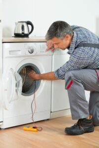 a man in overalls using a washing machine.