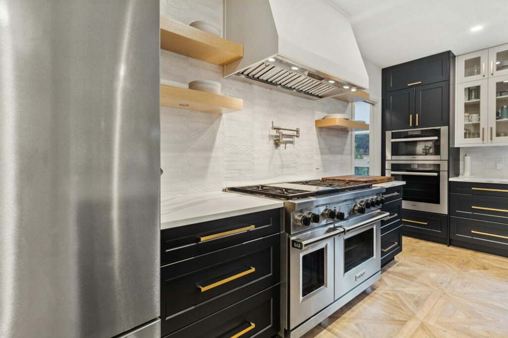 A black and gold kitchen with stainless steel appliances.
