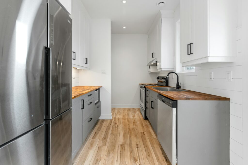 A white kitchen with wood floors and stainless steel appliances.