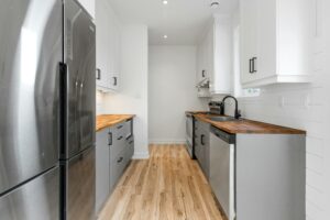 A white kitchen with wood floors and stainless steel appliances.