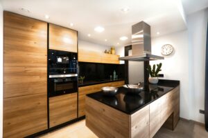 A kitchen with black counter tops and wooden cabinets.