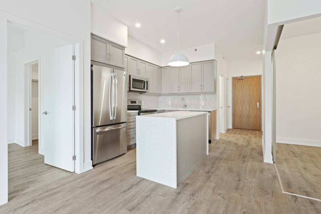 A white kitchen with stainless steel appliances and hardwood floors.