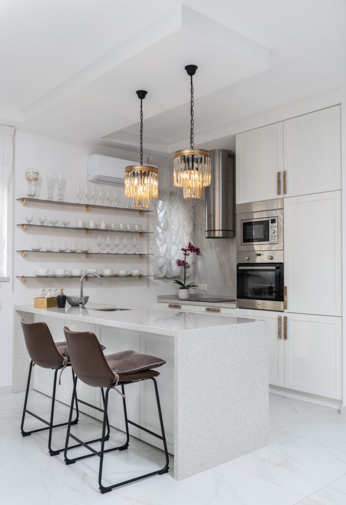 A white kitchen with marble counter tops and chairs.