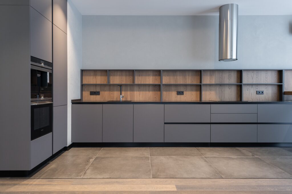 A modern kitchen with grey cabinets and wooden floors.