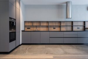 A modern kitchen with grey cabinets and wooden floors.