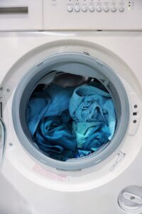 A white washing machine with blue clothes in it.