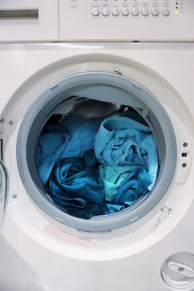 A white washing machine with blue clothes in it.