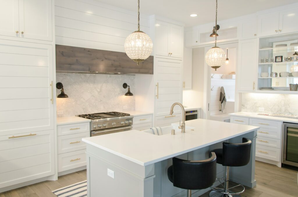 A kitchen with white cabinets and a bar stools.
