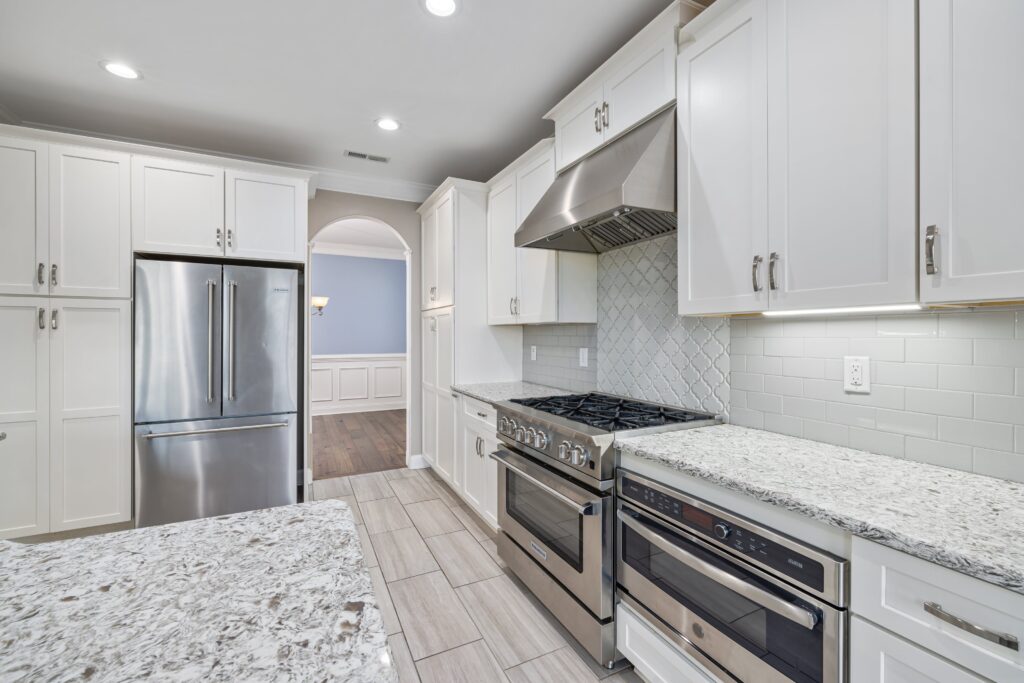 A white kitchen with stainless steel appliances and granite counter tops.
