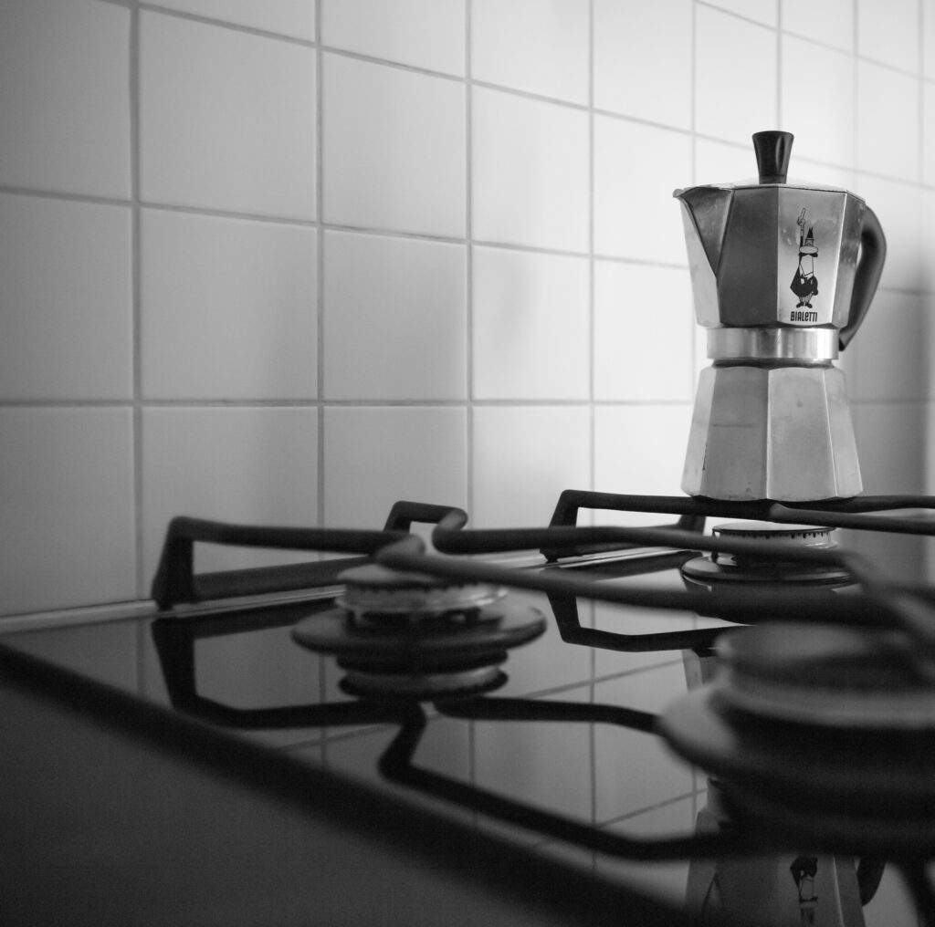 a black and white photo of a coffee pot on a stove.