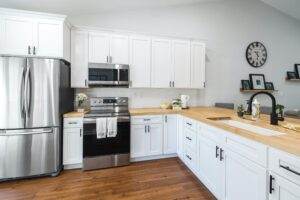 A white kitchen with stainless steel appliances and wood counter tops.