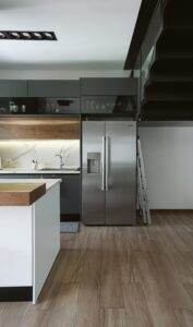 A modern kitchen with wooden floors and stainless steel appliances.