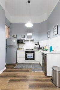 A small kitchen with blue walls and wooden floors.