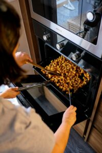 a woman removing food from an oven.