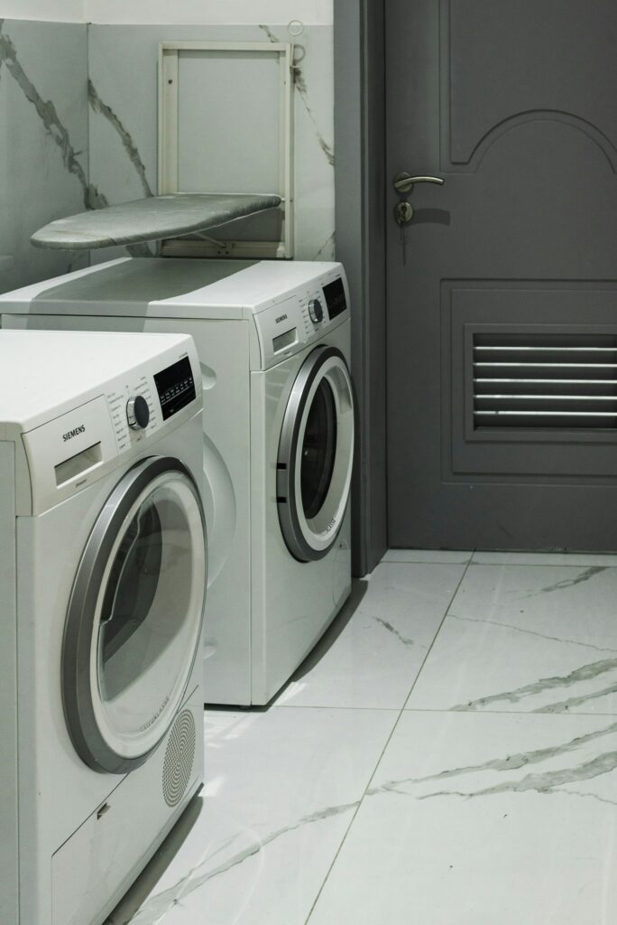 a laundry room with two washing machines and a door.