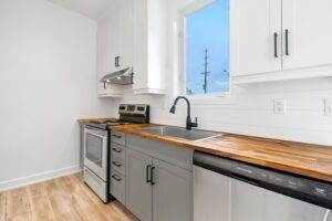 A kitchen with a stove, sink, and a window.