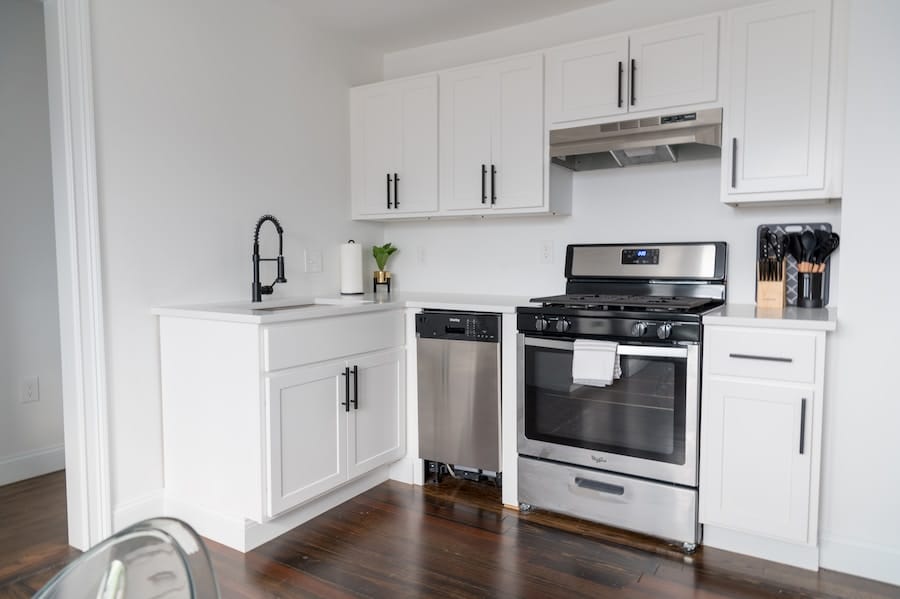 a kitchen with white cabinets and black appliances.