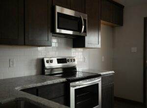 A kitchen with stainless steel appliances and black cabinets.