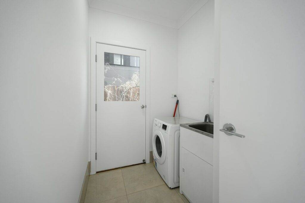A laundry room with a washing machine and door.
